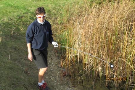 A golfer retrieves a ball from a water hazard